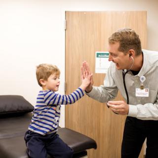 A cheerful interaction between a child and a healthcare professional, showcasing a friendly atmosphere in a medical setting.