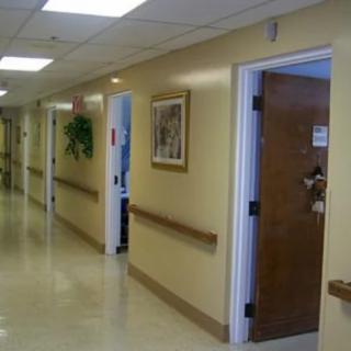 A quiet hospital hallway with several doors and overhead lighting.