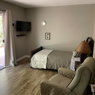 A cozy bedroom with a small bed, armchair, and wall-mounted TV.