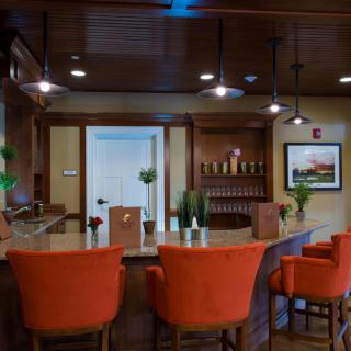 A cozy bar interior with bright orange chairs and warm lighting.