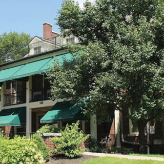 A charming house with green awnings and a lush garden.