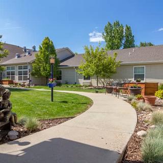 A well-maintained garden with a winding pathway leading to residential buildings on a sunny day.