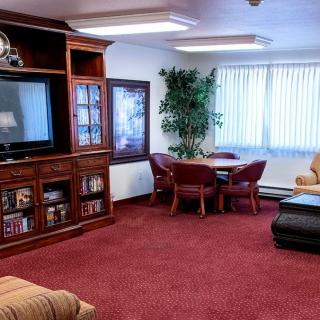 A cozy living room with a large TV, comfortable seating, and a red carpet.