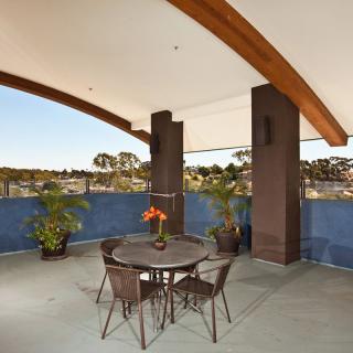 A spacious balcony with a table and chairs, complemented by potted plants and offering a scenic view.