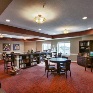 A spacious lounge area with tables, chairs, and bookshelves.