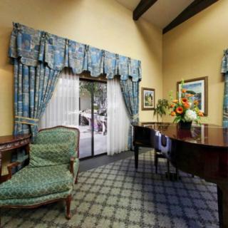 A stylish living room with a grand piano, patterned curtains, and elegant furniture.