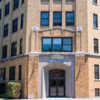 The image shows the entrance of a brick building with several windows.