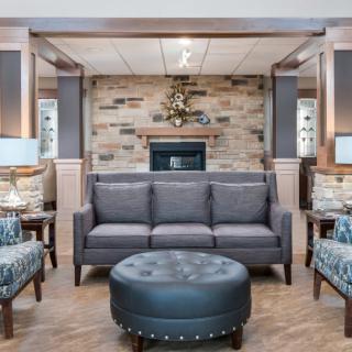 A cozy living room featuring a gray sofa, brick fireplace, and a round ottoman.