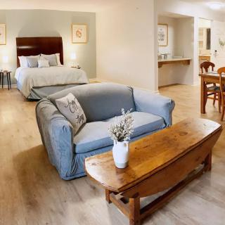 A cozy open-concept bedroom and living area featuring a bed, sofa, and dining table with warm decor.
