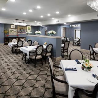 An elegant dining room with neatly arranged tables, upholstered chairs, and soft lighting creating a welcoming atmosphere.