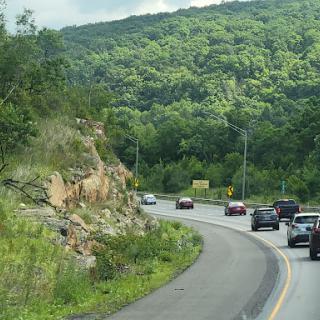 A scenic view of a curving road surrounded by lush green mountains.