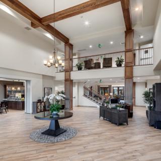 A spacious and modern lobby featuring a chandelier, wood beams, and comfortable seating.