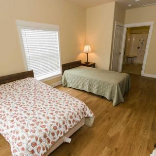 A cozy bedroom with two beds, wooden flooring, and a warm lamp.
