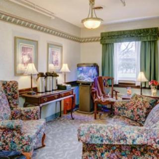 A traditional living room with floral armchairs, a television, and decorative lamps.