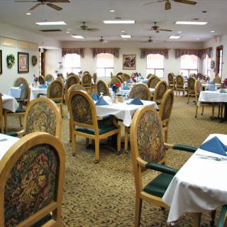 Spacious dining room with elegantly set tables and ornate chairs.