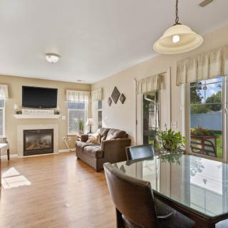 A modern living room with a fireplace and TV, adjacent to a dining area with ample natural light.