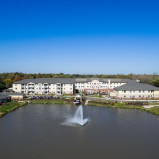 Aerial view of a large building complex with a fountain in the foreground and clear blue skies.