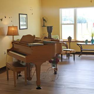 A cozy living room featuring a grand piano, warm lighting, and elegant decor.
