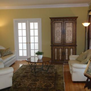 A cozy living room with sofas, an armoire, and a coffee table centered on a decorative rug.