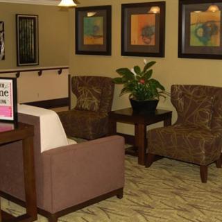 A cozy waiting room with comfortable chairs, a table, and decorative art on the walls.