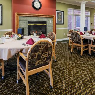 An elegantly set dining area with tables and chairs, featuring a central fireplace.