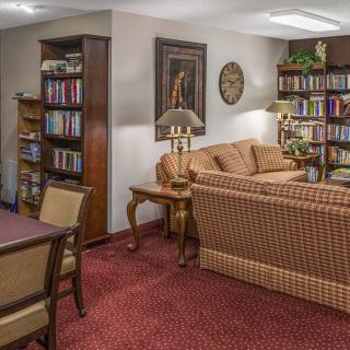 A cozy library room with a sofa, chairs, and shelves filled with books.