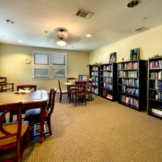 A cozy library room with bookshelves, tables, and chairs.