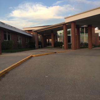 The entrance of a brick building under a partly cloudy sky.