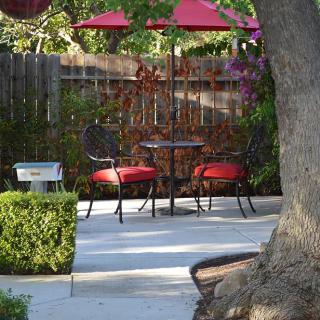 A tranquil backyard patio with red umbrella-shaded seating.