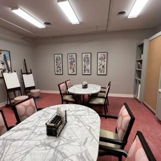 A modern meeting room with tables, chairs, and wall artwork.