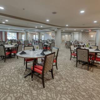 Spacious dining area with multiple tables and chairs, featuring elegant carpeting and soft lighting.