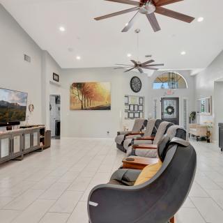 A modern living room with sleek seating, neutral colors, ceiling fans, and contemporary artwork.