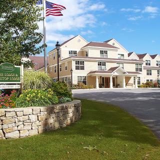 A welcoming hotel entrance with manicured landscaping and an American flag flying.
