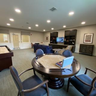 A spacious lounge area with comfortable seating, a television, and gaming tables.