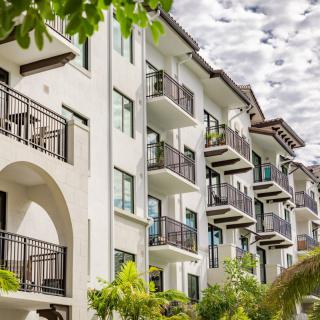 A modern apartment building with multiple balconies surrounded by greenery.