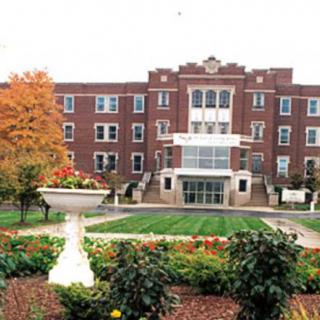 A college campus with a red-brick building and landscaped garden.