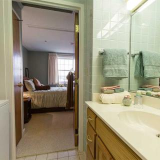 A view from a bathroom into a bedroom, featuring a sink and towels.