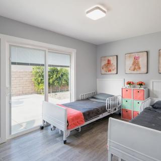 A modern kids' bedroom with twin beds and colorful decor, featuring large sliding doors that let in natural light.