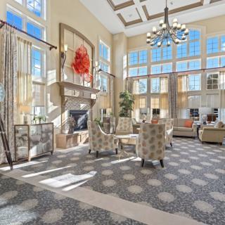 A spacious and bright living room with high ceilings, large windows, a chandelier, and modern furniture.