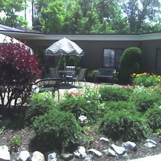 A tranquil garden with patio furniture and lush greenery.