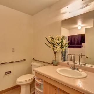 A clean bathroom with a sink, mirror, and decorative flowers.