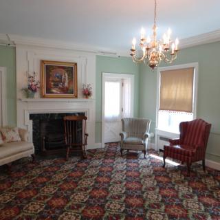 A vintage-style living room with a chandelier, fireplace, and classic armchairs.