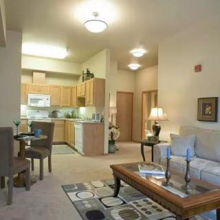 A cozy apartment interior featuring a living room with modern furniture, an adjacent dining area, and a kitchen in the background.