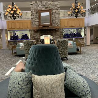 A cozy hotel lobby featuring elegant furniture, a stone fireplace, and stylish lighting.