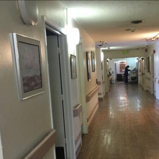 A long hospital corridor with doors and paintings on the walls.
