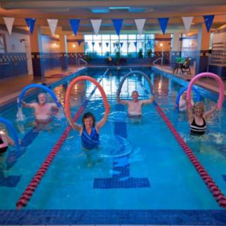 A group of people participating in a water aerobics class at an indoor swimming pool.