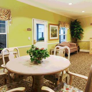 A cozy dining area with a round table and chairs, complemented by a sofa and indoor plants.