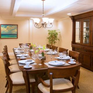 A well-lit dining room with a large wooden table set for a meal, accompanied by matching chairs and decorative elements.