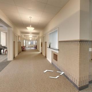 A modern hallway with carpeted floors and overhead lighting.