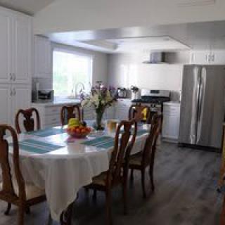 A bright kitchen and dining area with a table set for a meal, featuring stainless steel appliances and white cabinetry.